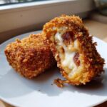 A crispy, golden-brown korean corn dog cut in half revealing melted mozzarella cheese and sausage inside.