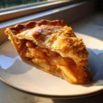A close-up shot of a thick slice of homemade apple pie showing gooey spiced apples and a flaky, golden crust.