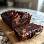 A rich, dark chocolate hot fudge brownie bread loaf with a slice cut, showing a marbled interior.