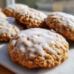 Close-up of several soft iced oatmeal cookies topped with a thick, shiny white glaze.