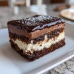 A decadent slice of three-layer Italian love cake featuring chocolate cake, white filling, and chocolate mousse topping.