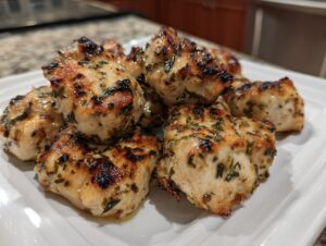 Close-up of grilled, herb-coated chicken pieces showcasing the results of the amazing chicken marinade.