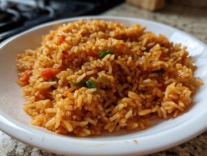 Close-up of a fluffy serving of vibrant orange Mexican rice recipe with visible pieces of tomato and green onion.