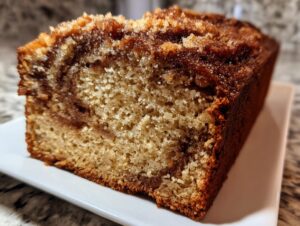 Close-up of a slice of moist cinnamon bread showing a rich swirl and sugary cinnamon streusel topping.
