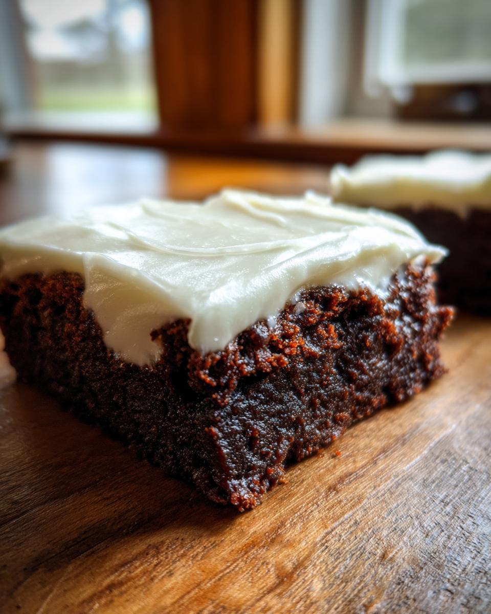 Close-up of a rich, dark gingerbread brownies square topped with thick white cream cheese frosting.