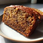 Close-up of a moist, dark brown slice of the best banana bread showing its dense, flavorful crumb texture.
