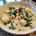 A close-up bowl of creamy olive garden chicken gnocchi soup, featuring shredded chicken, spinach, and potato gnocchi.