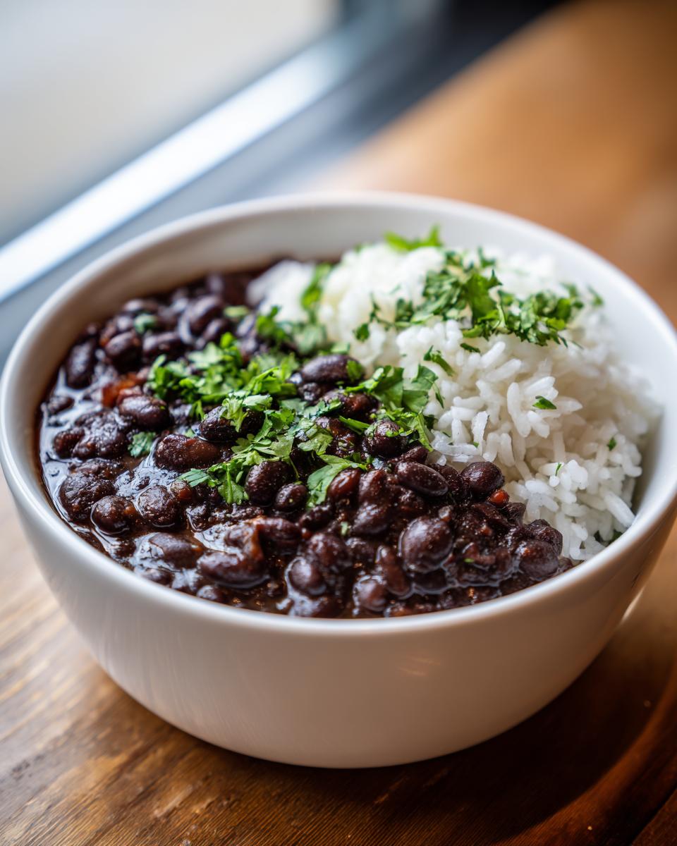 Close-up of a white bowl filled with savory black beans and rice, garnished with fresh cilantro.