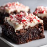 A rich, fudgy square of peppermint brownies topped with thick white frosting and crushed candy canes.