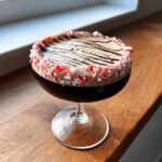 A rich peppermint espresso martini garnished with a crushed candy cane rim and chocolate drizzle.