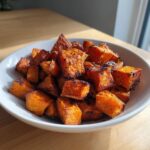 A white bowl filled with perfectly caramelized and slightly charred roasted sweet potatoes cubes.