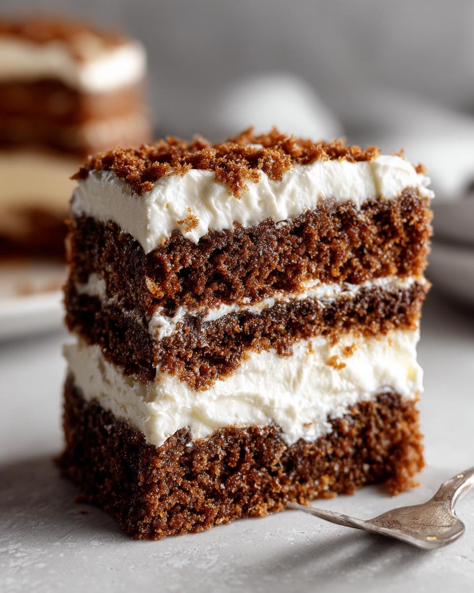 Close-up of a layered slice of gingerbread trifle showing dark cake layers and thick white cream filling.