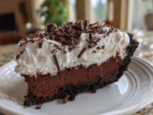 A decadent slice of chocolate mud pie featuring a dark crust, rich filling, whipped cream, and chocolate shavings.
