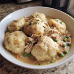 A close-up bowl of rich slow cooker chicken and dumplings, topped with fresh parsley.
