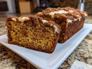 Close-up of a slice of moist snickerdoodle zucchini bread with a cinnamon streusel topping and light glaze.