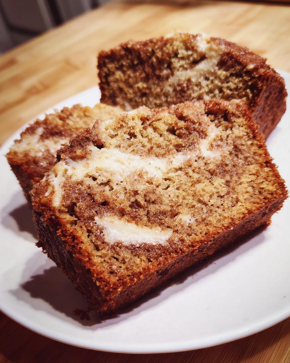Three moist slices of snickerdoodle zucchini bread featuring a cinnamon swirl and cream cheese filling on a white plate.