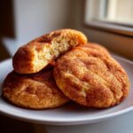 Close-up of soft pumpkin snickerdoodle cookies coated in cinnamon sugar, one cookie broken open showing the texture.