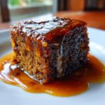 Close-up of a rich, moist square of sticky toffee pudding recipe drenched in thick toffee sauce.