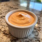 Close-up of creamy, orange-pink homemade big mac sauce served in a small white fluted ramekin.