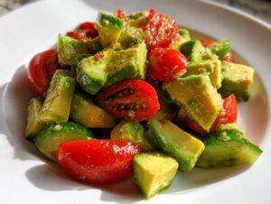 Close-up of chunky avocado salad mixed with bright red halved cherry tomatoes, lightly dressed.