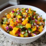 Close-up of fresh, chunky peach salsa featuring diced yellow peaches, red onion, and cilantro.