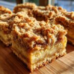 Close-up of a square portion of apple pie bars featuring a thick, golden crumble topping and visible apple filling.