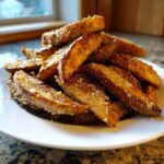 A pile of golden brown, crispy potato wedges seasoned with grated Parmesan cheese.