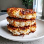 Three golden-brown, pan-fried crispy rice cakes stacked on a white plate.