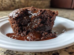 A close-up of a serving of chocolate cobbler revealing a molten, gooey fudge layer spilling onto the white plate.