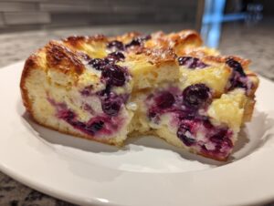 Close-up of a moist slice of Blueberry French Toast Casserole showing creamy filling and burst blueberries.