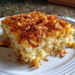 A close-up of a creamy casserole slice, likely Monterey Chicken Spaghetti, topped with crispy fried onions.